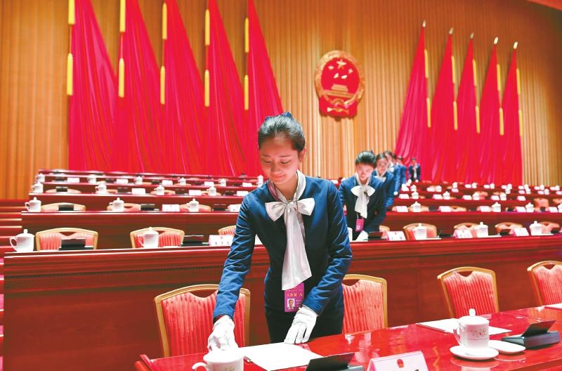 图为昨(25)日,工作人员在大会会场摆放纸和笔   省十三届人大一次会议
